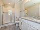 Bright bathroom featuring a tiled shower with glass door, a granite-topped vanity with white cabinets and modern fixtures at 11507 Valley Oak Ln, Stanfield, NC 28163