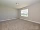 Cozy bedroom featuring neutral carpet and a bright window with a view of the neighborhood at 11507 Valley Oak Ln, Stanfield, NC 28163