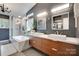 Modern bathroom features double vanities, a luxurious tub, a glass enclosed shower, and sleek fixtures at 11615 Chadburn Ln, Charlotte, NC 28215