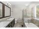 Bathroom featuring double vanity, framed mirrors, and glass enclosed tub and shower at 13010 Indian Hills Ln, Charlotte, NC 28278