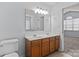 Bright bathroom featuring double sinks, oak cabinets, and a large mirror at 15280 Leslie Brook Rd, Huntersville, NC 28078