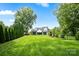 Large backyard featuring a lush lawn, a new construction home, and a line of trees at 16112 Terry Ln, Huntersville, NC 28078