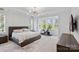 Bright primary bedroom featuring a large bed, chandelier and workout equipment at 16112 Terry Ln, Huntersville, NC 28078
