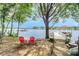 Scenic waterfront view with a covered dock and red chairs on the shore, perfect for relaxing and enjoying the lake at 174 Hickory Hill Rd, Mooresville, NC 28117
