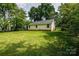 Lush backyard featuring a well-maintained lawn, mature trees, and a charming exterior at 1801 Teddington Dr, Charlotte, NC 28214