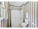 Bathroom featuring bathtub with showerhead, toilet, and vertically-striped wallpaper at 1958 Cameron Heights Cir, Denver, NC 28037