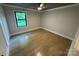 Bright, neutral bedroom with hardwood floors, updated trim, a ceiling fan, and a view of the yard at 209 Falcon Dr, Concord, NC 28025