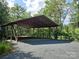 Large metal carport surrounded by lush greenery, offering ample covered parking at 209 Falcon Dr, Concord, NC 28025