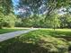 Well-maintained front yard with lush green grass, mature trees, and a long paved driveway at 209 Falcon Dr, Concord, NC 28025