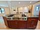 Spacious kitchen island featuring a cooktop, granite countertop, and wood cabinetry, leading to a living area with fireplace at 209 Falcon Dr, Concord, NC 28025