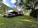 Spacious backyard with lush green grass, mature trees, and an outdoor living area at 2411 Rebecca Ave, Charlotte, NC 28208