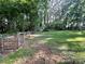 Large backyard featuring a mix of grassy areas, wooded space, and a fenced perimeter at 2411 Rebecca Ave, Charlotte, NC 28208