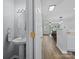 Hallway view of a half bathroom, offering pedestal sink, neutral walls and access to living spaces at 3414 Broadwick St, Charlotte, NC 28213