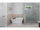 Bathroom featuring a soaking tub with decorative tile surround and a glass enclosed shower with small window for natural light at 3701 Table Rock Rd, Charlotte, NC 28226