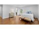 Well-lit bedroom with hardwood floors, a comfortable bed, a chest of drawers, and a door to the ensuite bathroom at 3701 Table Rock Rd, Charlotte, NC 28226