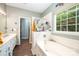 Bright bathroom featuring tiled tub, window, white vanity, and wood-look floors at 4703 David Cox Rd, Charlotte, NC 28269