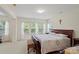 Bright bedroom featuring a large bed, three windows, and neutral walls at 4966 Riverview Dr, Harrisburg, NC 28075