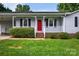 Inviting single-story home with a covered front porch, red front door, and green landscaping at 5445 Creekwood Dr, Salisbury, NC 28147