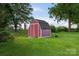 A backyard storage shed is conveniently situated in a grassy yard with a fenced enclosure beyond at 5445 Creekwood Dr, Salisbury, NC 28147