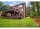 Brick house with multi-level wooden decks, green lawn with fence and wooded area in the background at 6016 Graburns Ford Dr, Charlotte, NC 28269