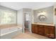 Bright bathroom with a soaking tub and wooden vanity with granite countertops at 7151 Plough Dr, Mint Hill, NC 28227