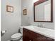 Cozy powder room featuring a wooden vanity, framed decor, and toilet, with a modern chrome faucet at 7151 Plough Dr, Mint Hill, NC 28227