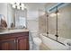 Cozy bathroom with a marble vanity, shower-tub combination with black-framed sliding glass door at 8016 Pemswood St, Charlotte, NC 28277
