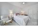 Bright bedroom features a queen bed, bedside table and an armchair by a window at 8016 Pemswood St, Charlotte, NC 28277