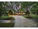 Stunning stone-accented home with well-manicured lawn, mature trees, and a spacious driveway leading to a three-car garage at 8016 Pemswood St, Charlotte, NC 28277
