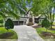 Attractive home featuring a stone facade, well-maintained landscaping, and a driveway leading to a three-car garage at 8016 Pemswood St, Charlotte, NC 28277