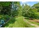 An idyllic stone path in the lush backyard is surrounded by greenery and mature trees at 8900 Cumbria Ct, Huntersville, NC 28078