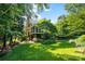 A beautiful backyard features lush grass and a screened in porch viewed through mature trees at 8900 Cumbria Ct, Huntersville, NC 28078