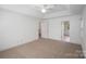 Spacious bedroom featuring neutral carpet, tray ceiling, ceiling fan, and views to bathroom at 8900 Cumbria Ct, Huntersville, NC 28078