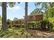 Brick home with a wooden deck, framed by mature trees and lush landscaping in a serene backyard setting at 1024 Regency Dr, Charlotte, NC 28211