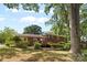 Expansive backyard view showcasing a brick home with a wooden deck, surrounded by lush greenery at 1024 Regency Dr, Charlotte, NC 28211