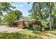 Brick home featuring a wooden deck and driveway, bordered by well-maintained landscaping and mature trees at 1024 Regency Dr, Charlotte, NC 28211