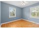 Comfortable bedroom featuring blue walls, hardwood floors, two windows, and ample natural light at 1024 Regency Dr, Charlotte, NC 28211