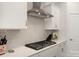 Modern kitchen with stainless steel hood, sleek cooktop, tile backsplash, and white cabinets at 11031 Larkslea Ln, Charlotte, NC 28278