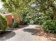 View of the backyard with a gravel driveway, lush trees, and a glimpse of a shed at 310 E Houston St, Monroe, NC 28112