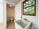 Laundry room with a utility sink, tile floors, and natural light from a large window at 310 E Houston St, Monroe, NC 28112
