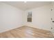 A bright bedroom featuring wood-look floors, a single window, and a door at 318 Sixth St, Belmont, NC 28012