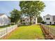Expansive backyard with well-maintained lawn, a white picket fence, and mature shade trees offering a peaceful outdoor setting at 411 Carlisle Dr, Indian Trail, NC 28079