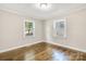 Well-lit bedroom featuring hardwood flooring, light walls, white trim, and two windows at 4413 Tillman Rd, Charlotte, NC 28208