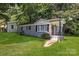 View of the painted brick exterior, lush green lawn, and covered porch with black railings at 4413 Tillman Rd, Charlotte, NC 28208
