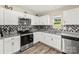 Modern kitchen featuring stainless steel appliances, granite countertops, white cabinets, and checkerboard backsplash at 473 Wendover Dr, Salisbury, NC 28147