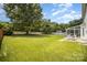 Expansive backyard featuring lush green grass, mature trees, and a charming patio area at 4835 Chesney Nw St, Concord, NC 28027