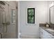 Bright bathroom featuring a glass-enclosed shower, white vanity, and a window offering natural light at 7011 Chateau Bordeaux Ln, Charlotte, NC 28270