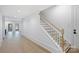 Bright hallway with hardwood floors leads to a staircase with white risers and natural wood railing at 7011 Chateau Bordeaux Ln, Charlotte, NC 28270