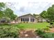 View of the backyard featuring a green lawn, flower beds, mature trees, deck, and ample space for outdoor activities at 7164 Moss Point Dr, Charlotte, NC 28277