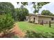 The backyard featuring a lush green lawn, mature trees, and garden beds, creating a private and serene outdoor oasis at 7164 Moss Point Dr, Charlotte, NC 28277